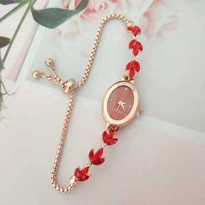 Macro view of adjustable rose gold leaf watch featuring red crystals and quartz dial