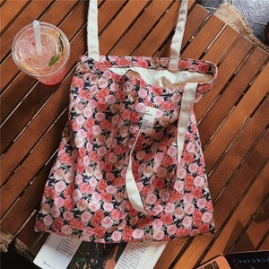 Detailed view of pink rose pattern canvas tote bag with woven handles and brand label