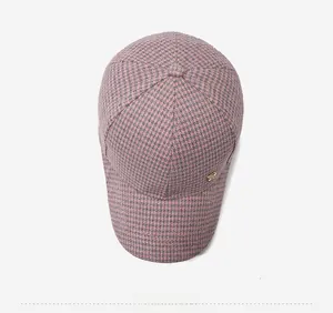 Detailed top view of a pink houndstooth baseball cap with golden metal side logo