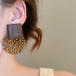 Detailed view of large square wood and beaded round cluster earrings on a model