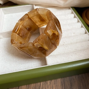 Macro view of geometric amber resin links with marble texture in a jewelry display box