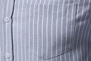 Detail of chest pocket and white buttons on blue vertical striped cotton linen shirt