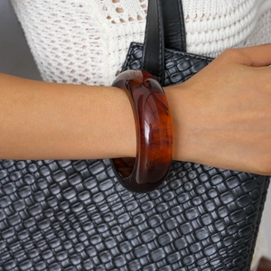 Close-up of translucent amber resin bangle with textured finish on a model's wrist