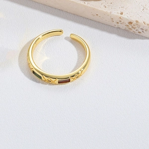 Detail of cross ring with red and green stones and diamond texture on gold band