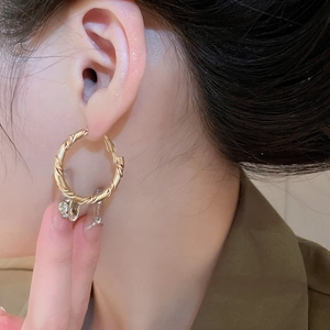 Close-up of golden twisted hoop earrings on a model showing the metallic texture