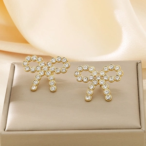 Macro detail of gold-plated bow earrings with pavé rhinestones on a velvet display