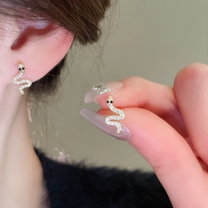 Close-up of gold snake earrings with micro-set rhinestones and black gem eyes