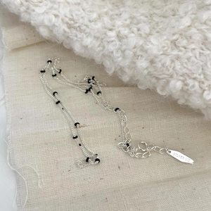 S925 sterling silver beaded necklace with black enamel accents on a soft fabric background