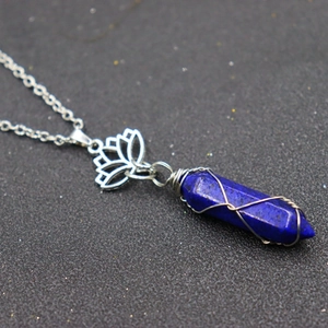 Macro detail of hexagonal blue crystal pendant with wire wrap and lotus metal charm