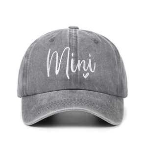 Close-up of grey washed denim cap featuring white Mini embroidery and a small heart