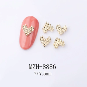 Macro shot of 7x7.5mm gold heart nail charms with textured finish for DIY manicure