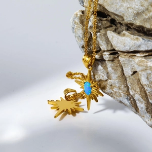 Close-up of gold star pendants with blue opal on a natural rock background