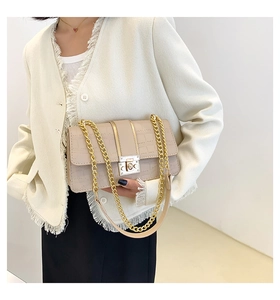 Detailopname van beige krokodillenpatroon en gouden metalen sluiting op de tas met ketting