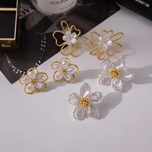 Detailed macro shot of three flower-shaped pearl earrings in elegant gold finish