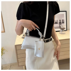 Sac à main argenté avec base incurvée et poignée nouée sur un fond intérieur minimaliste