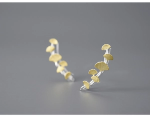 Macro shot of silver and gold ginkgo leaf earrings with brushed metal texture details