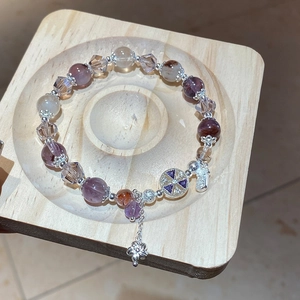 Macro view of amethyst bead bracelet with silver flower charms on a wooden tray