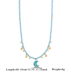 Detail of beaded necklace with blue moon pendant, crystal accents and golden charms