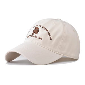 Detail of embroidered brown bear and text on a beige cotton baseball cap with ventilation holes