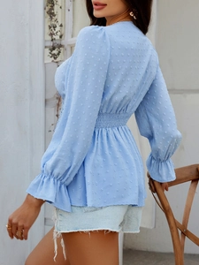 Détail du haut bleu à col en V avec texture à pois et poignets à volants élégants