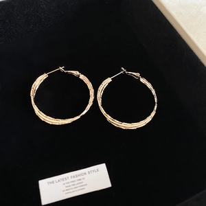 Detail of twisted gold hoop earrings placed in a black velvet jewelry box gift setting