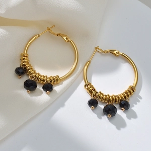 Detail of gold U-shaped hoop earrings featuring three faceted black beads on silk