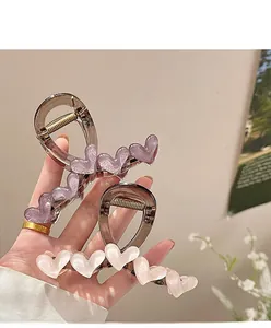 Detail of luxury acrylic heart hair claw clips with elegant pearlescent texture finish