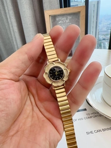 Detailed view of flower-shaped golden vintage watch with black dial and metal strap