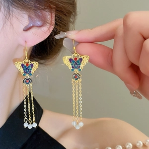 Elegant gold plated butterfly earrings with enamel lotus and tassels on female model