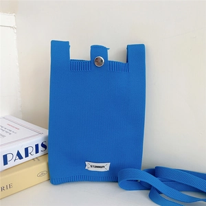Detail of Klein blue knitted phone bag with silver metal button and Stannum label