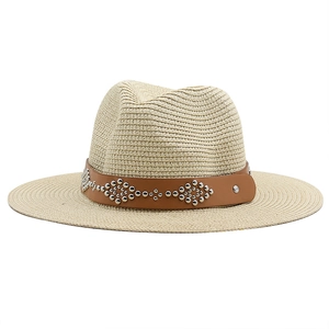 Detailed close-up of straw sun hat with brown leather band and silver metal rivets