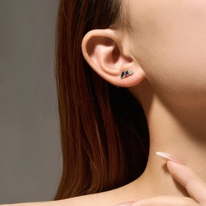Macro shot of S925 silver teardrop earrings with blue and white crystals on a model ear