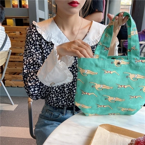 Detail of green canvas lunch tote bag featuring a creative swimmer pattern in a cafe setting