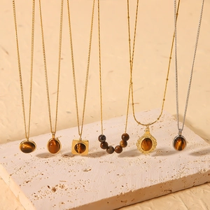 French retro 18k gold plated necklaces with natural tiger eye pendants on beige stone