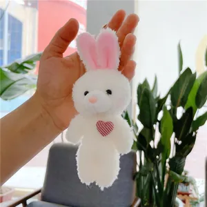 Close-up of white plush bunny keychain with red striped heart and soft fleece texture