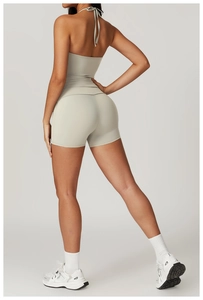 Back view of a light gray backless halter neck yoga top and matching high waist shorts set