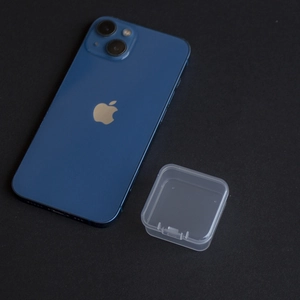 Mini transparent square plastic storage box shown next to a smartphone for size scale