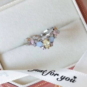 Macro shot of an adjustable silver ring with colorful zircons in a beige jewelry box