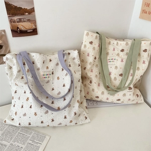 Detail of white seersucker tote bag with bear pattern and green and purple straps