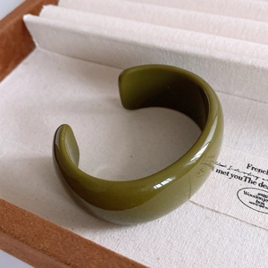 Close-up of a wide olive green resin cuff bracelet with a smooth glossy finish