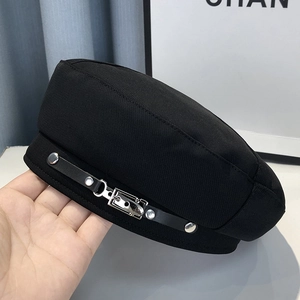 Detail of black beret with leather trim and silver metal buckle decoration