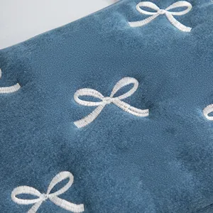 Détail de la broderie nœud blanc sur denim bleu pour sacoche d'ordinateur