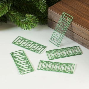 Green metal Christmas ornament hooks in linked rows with festive pine branch decor