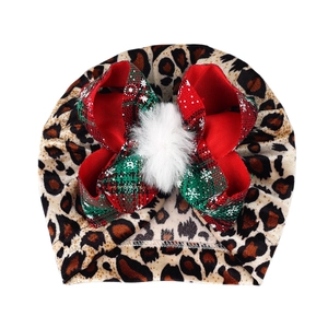 Leopard print baby turban hat with festive red and green bow and white pom pom