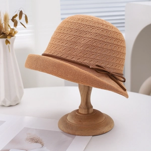 Breathable woven sun hat with side bow detail on a wooden stand for summer sun protection