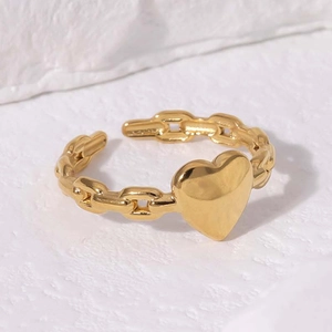 Gold heart ring with chain-link band adjustable design on white textured background
