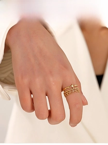 Three-piece gold stacked rings featuring star motif and hollow lace textures worn on model