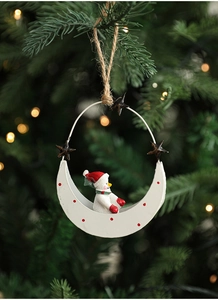 Detail of Christmas metal moon snowman hanging ornament on a warm festive tree branch