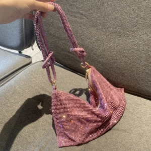 Detail of pink rhinestone handbag featuring a decorative knot on the sparkling strap