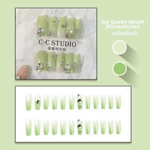 Detail of long trapezoid press-on nails with green gradient and heart-shaped rhinestones